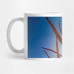 Spiky aloe green and orange leaves against blue sky Mug